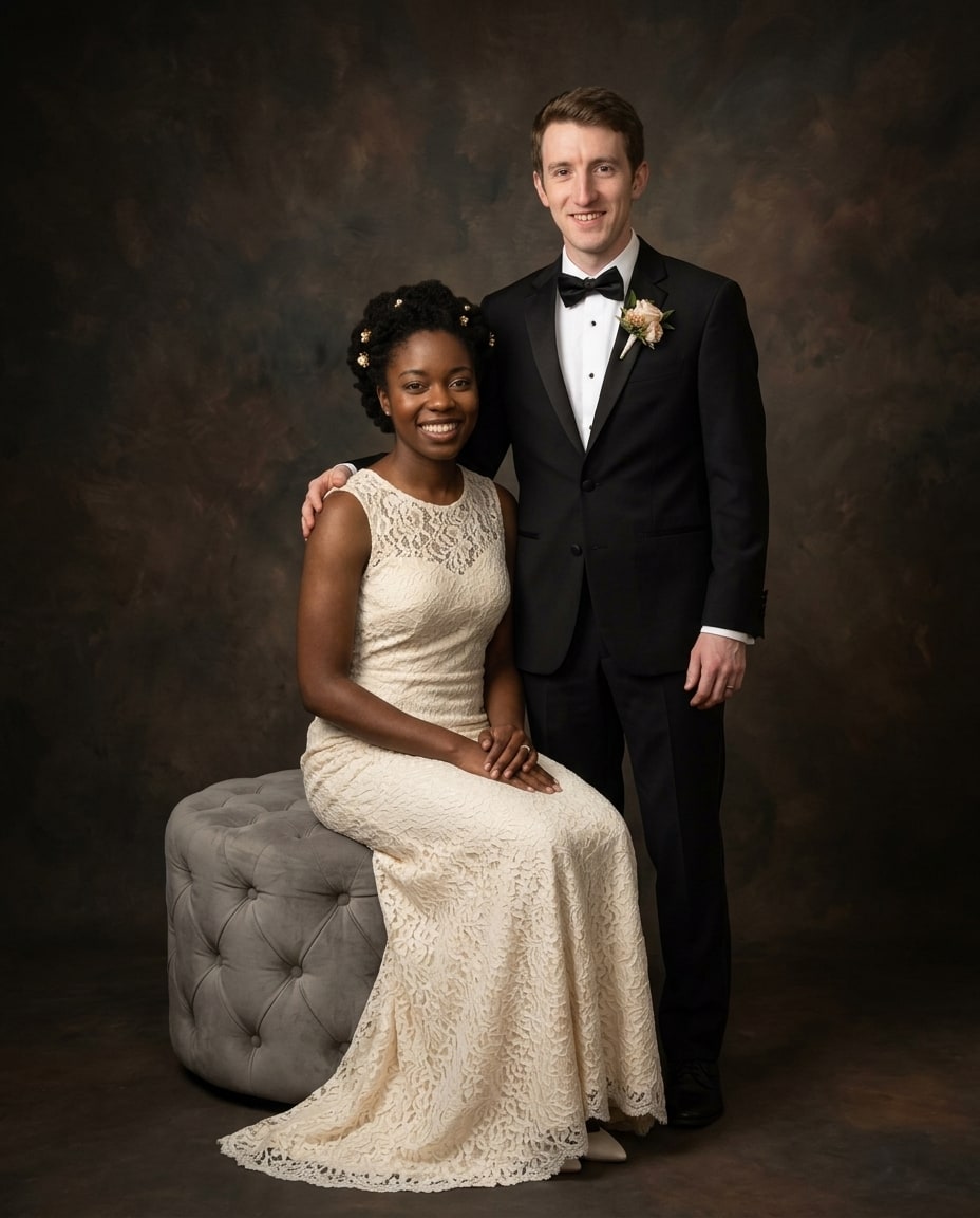 A formal wedding portrait on canvas depicting a smiling woman in a cream lace dress seated beside a man in a black tuxedo against a dark painterly background.